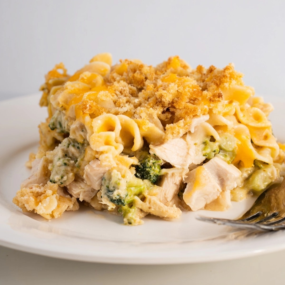 Close-up of a cheesy Broccoli Cheddar Chicken Noodle Casserole slice with tender chicken and noodles.