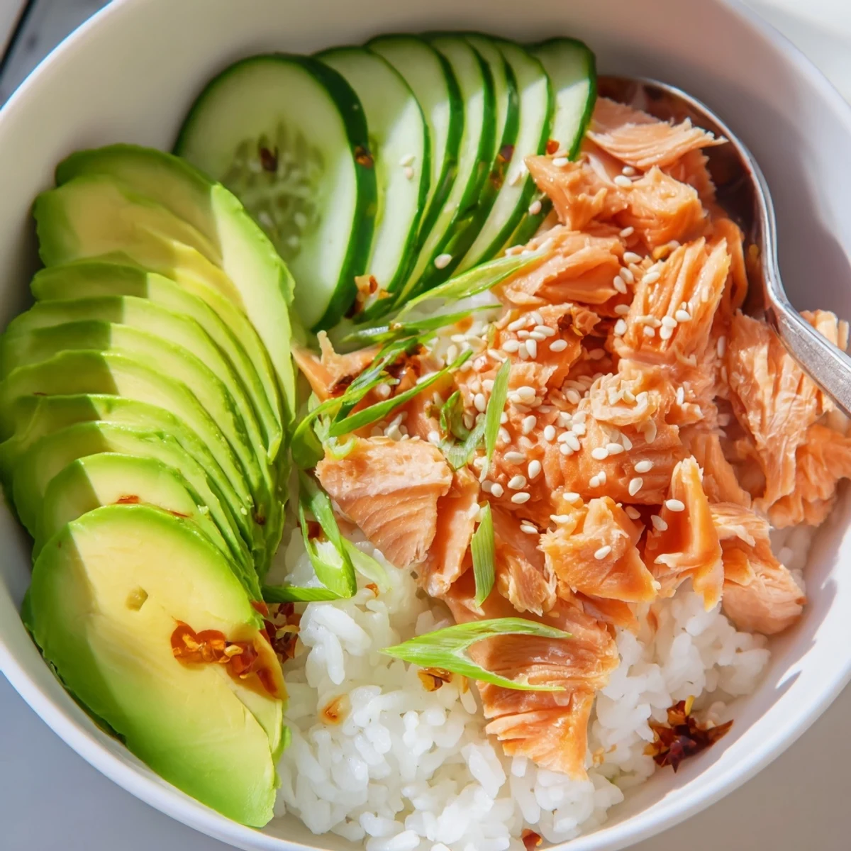 Delicious leftover salmon and rice bowl topped with fresh avocado and cucumber slices.  