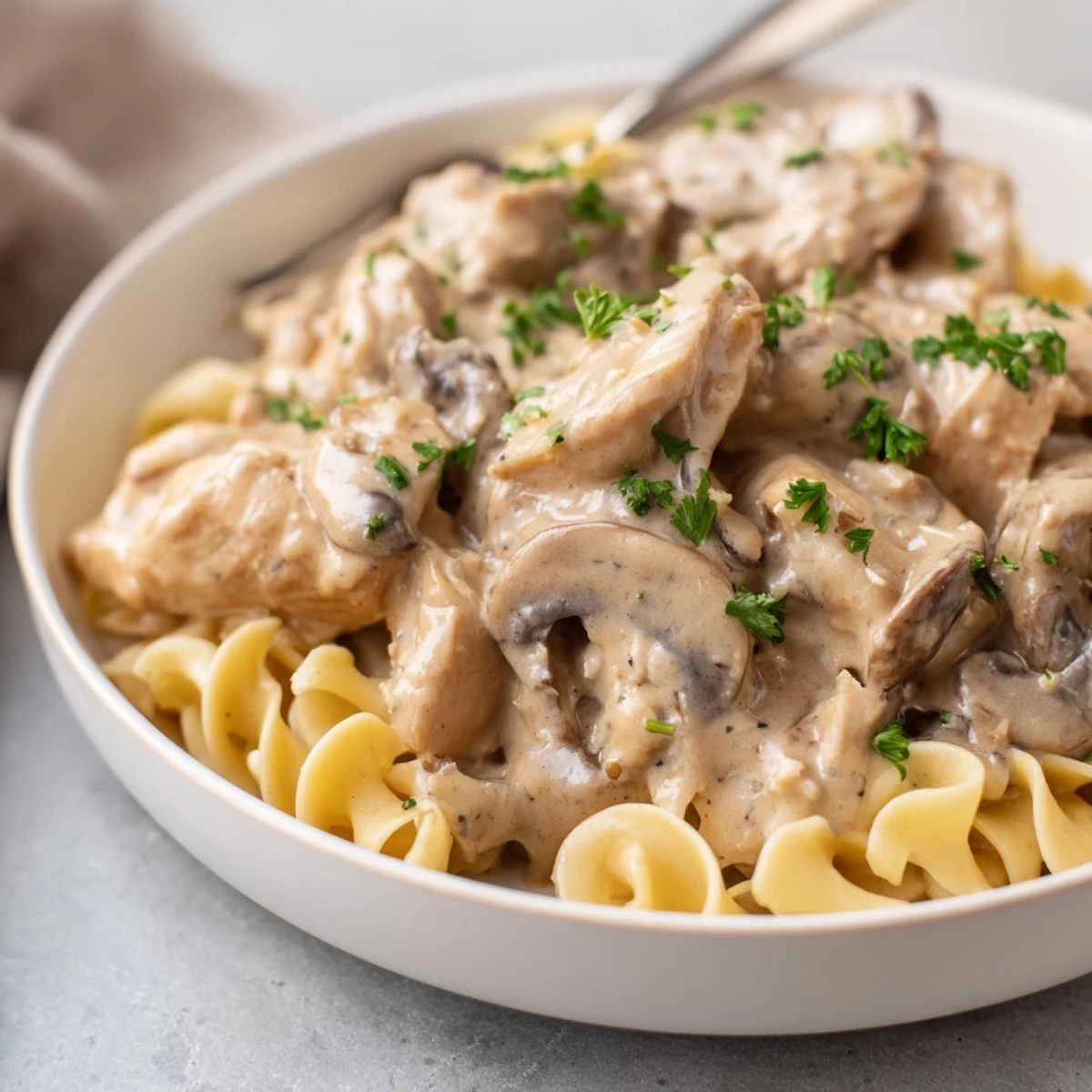 Creamy Chicken Stroganoff served over tender egg noodles, garnished with fresh parsley.  