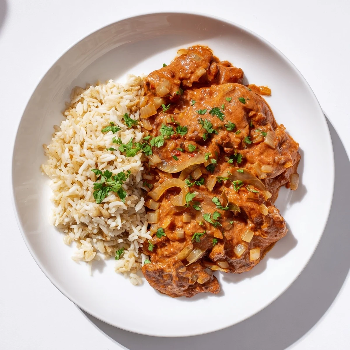 Tender butter chicken with creamy sauce, served with fragrant basmati rice pilaf, a warm Indian meal.