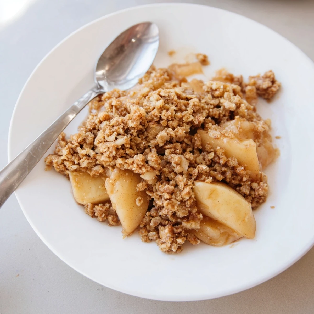 A close-up image of fresh, baked apple crisp, ready to eat with a scoop of vanilla ice cream.