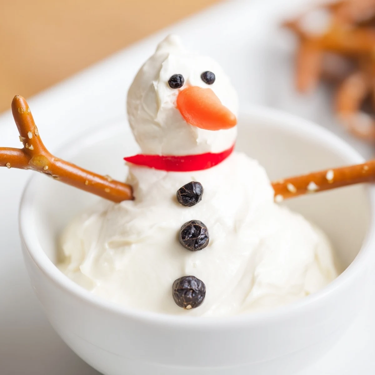 Creamy melted Snowman Dip, a festive appetizer with carrot noses and pretzel arms, perfect for parties.