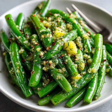 Garlic Butter Green Beans with vibrant pickle crunch beside a delicious dinner on a white plate.