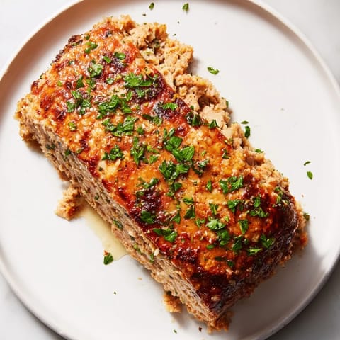 Warm, comforting image: sliced Garlic Parmesan Chicken Meatloaf with a parsley garnish, ready to serve.