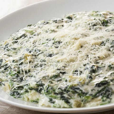 Golden-brown, cheesy Spinach Artichoke Dip, ready to be scooped up and enjoyed with friends.