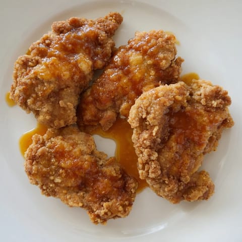 This close-up showcases crispy fried hot honey butter chicken, drizzled with sweet and spicy sauce.