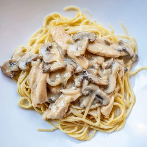 Tender chicken and skinny spaghettini tossed in a velvety mushroom cream sauce, topped with grated Parmesan and fresh parsley for a comforting Italian-inspired dinner.  