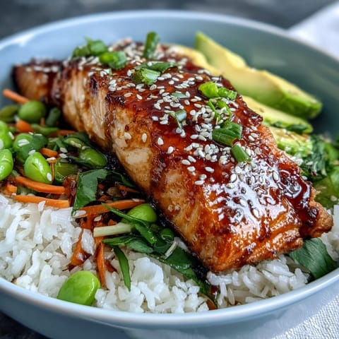 Close-up of a soy ginger salmon bowl garnished with creamy avocado slices, fresh green onions, and toasted sesame seeds.